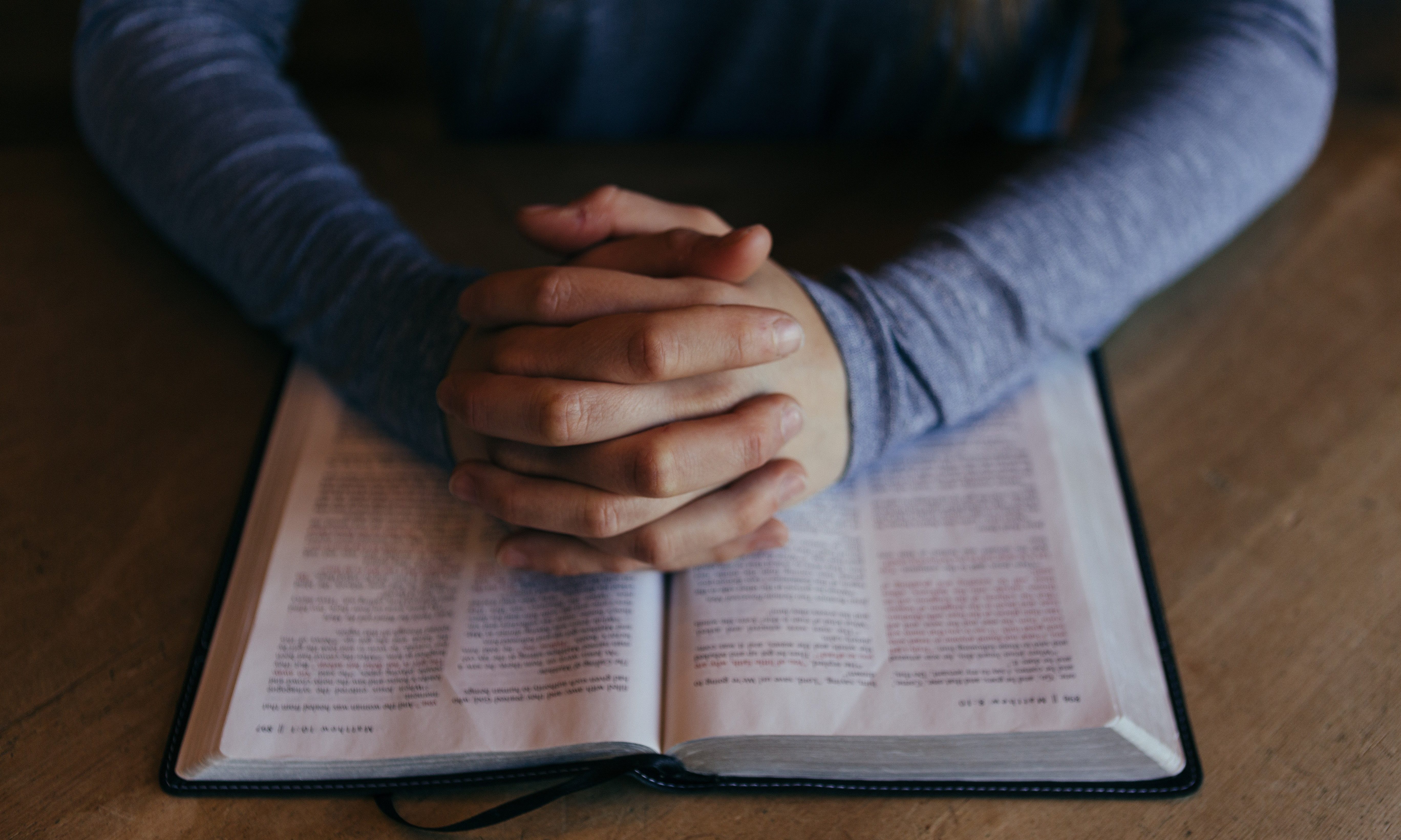 Hands pray on bible