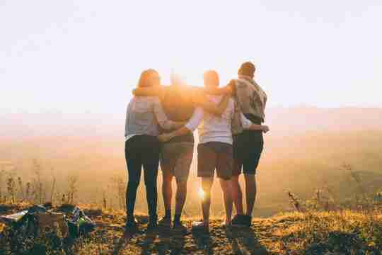 four-person-standing-on-cliff-in-front-of-sun