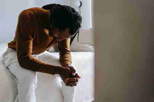 desperate-black-man-sitting-on-bed-in-deep-thoughts