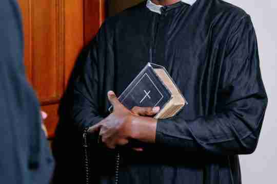 man-in-black-long-sleeve-shirt-holding-white-and-black-book