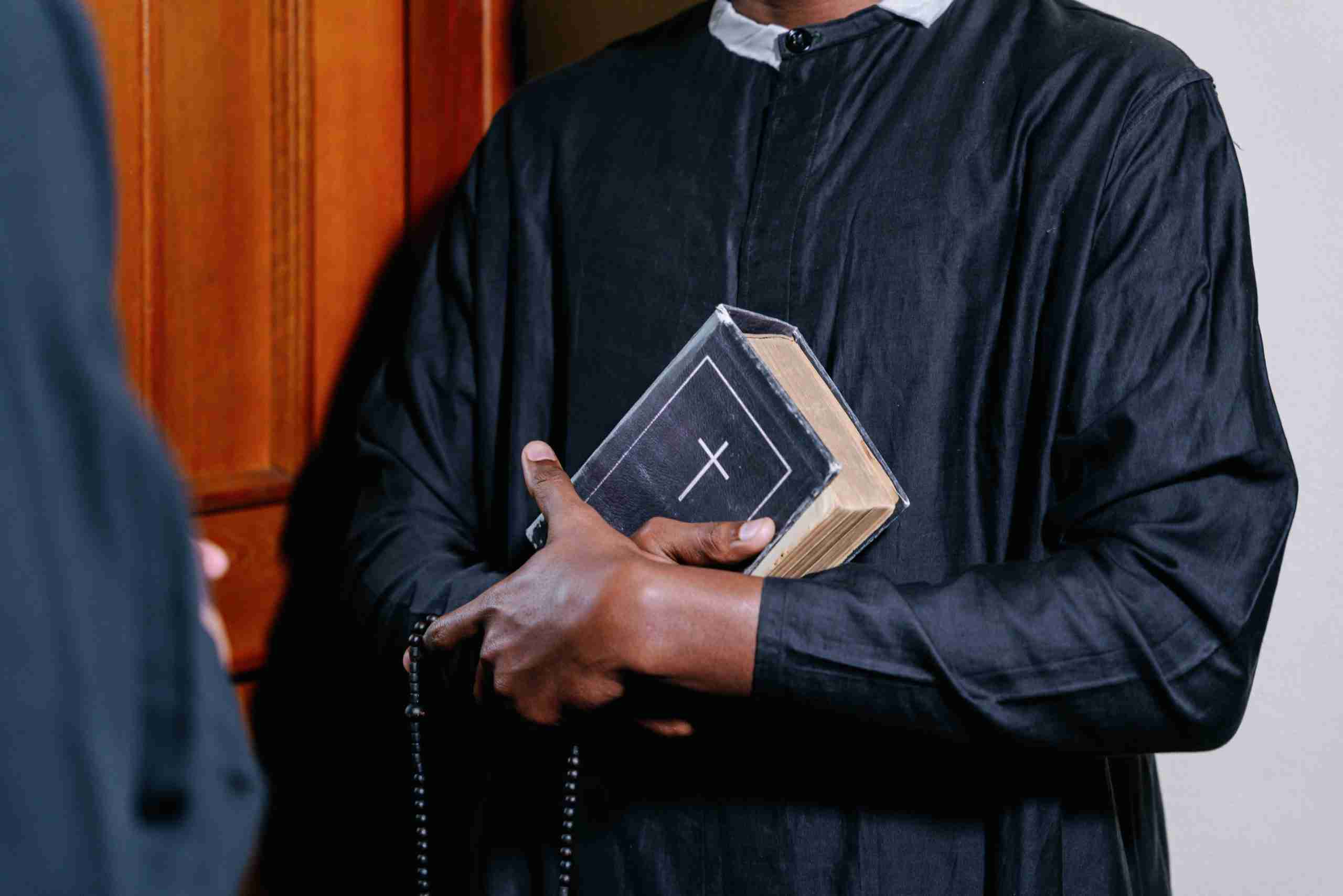 man-in-black-long-sleeve-shirt-holding-white-and-black-book