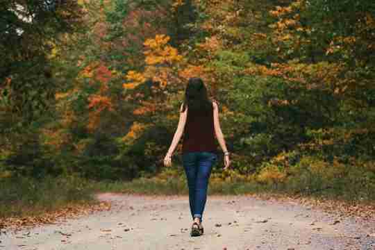woman-in-brown-sleeveless-dress-and-blue-jeans-standing-on-gray-path-road