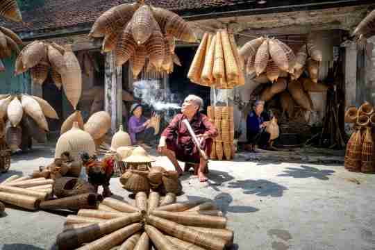 vietnamese-man-smoking-among-women-working-on-bamboo-fish-traps